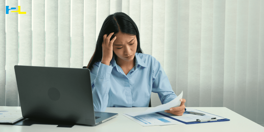 A woman sitting at a table with papers and a laptop.