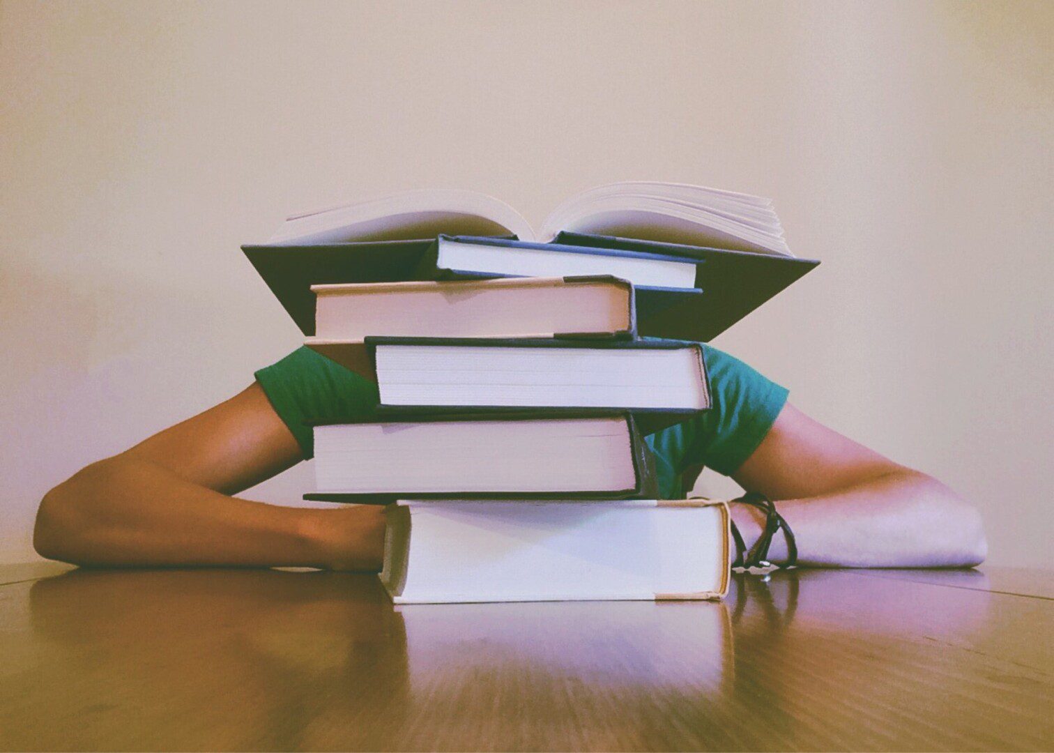 A person sitting at the table with books on their head